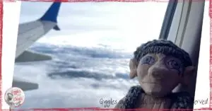A wooden puppet looking out of a plane window