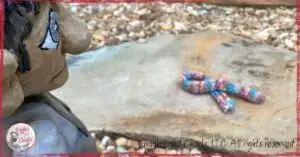 A wooden puppet, looking at a knitted scarf on the ground