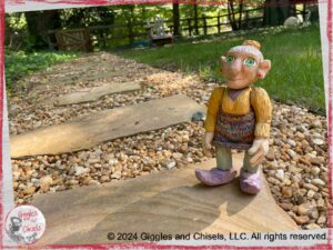 Picture of a colorful wooden puppet, on a stone path.