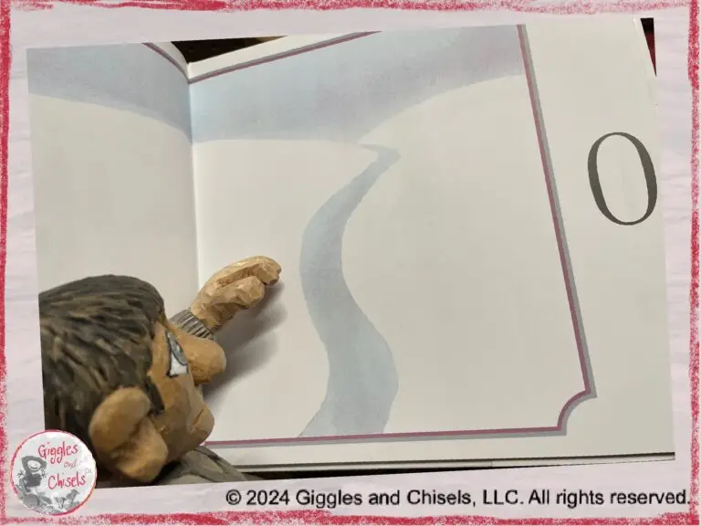 Maurice, a wooden puppet in grey tone, looking at a page of the book Anno's counting book