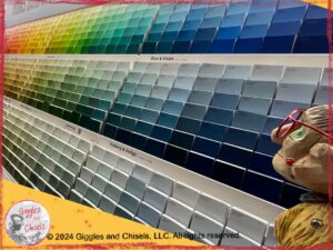 A picture of Mme Rigolotte, a wooden puppet, in front of a wall of paint swatches