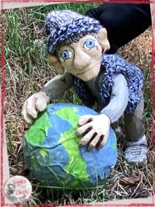 Maurice, a wooden puppet in grey tones, holding a earth made out of paper mache