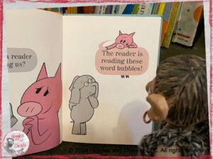 A picture of Maurice, a wooden puppet, listening to the book We are in the Book, by Mo Willems