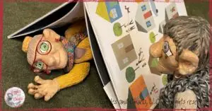 Two wooden puppets, one hiding under a picturebook