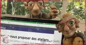 Two wooden puppets, next to a computer screen