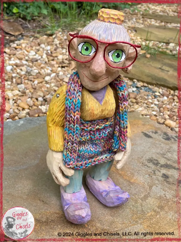A wooden puppet, in colorful colors and red glasses on a stone pathway.