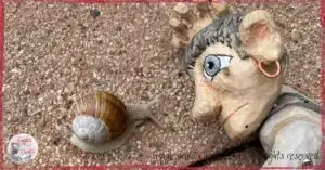 Maurice, a wooden puppet, looking at a snail