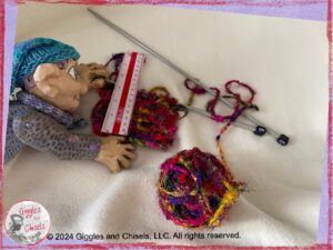 Petite Clothilde, a wooden puppet in purple and blue colors, measuring a knitted piece.
