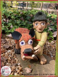 Pierre-Qui-Roule, a wooden puppet in green shades, next to an imaginary animal, with purple eyes, orange fur, and black ears.