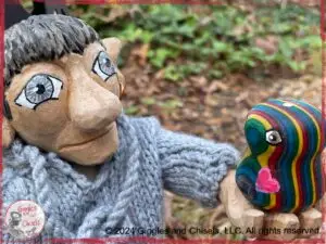 Maurice, a wooden puppet, holding a little creature, turned on a lathe, in rainbow colors.