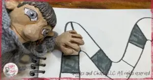 A picture of Maurice, a wooden puppet, in front of a board game