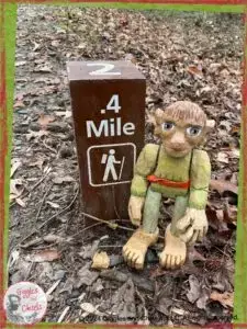 A picture of Pierre Qui Roule, a wooden puppet, in front of a mile marker