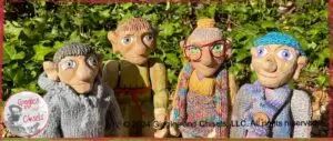A picture of four wooden puppets, one in grey, one in green, one in blue and purple, and one in rainbow colors