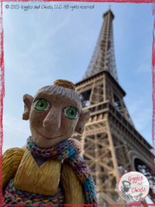 Mme Rigolotte, a wooden puppet, in front of the Eiffel Tower