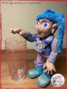 Petite Clothilde, a wooden puppet in front of a measuring cup