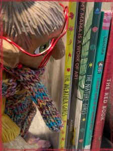 Mme Rigolotte, a wooden puppet, looking at five picturebooks