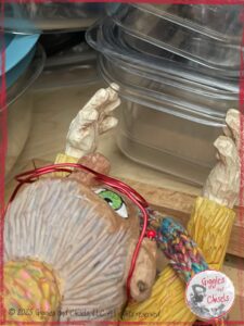 Mme Rigolotte, a wooden puppet, in front of a pile of plastic containers