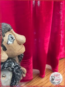 Maurice, a wooden puppet, in front a red curtain