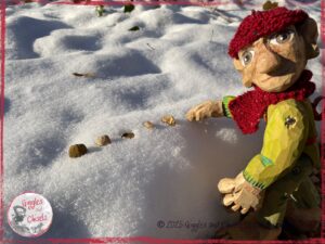 A picture of Pierre qui Roule, a wooden puppet, playing in the snow