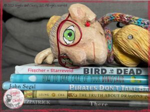 Mme Rigolotte, a wooden puppet, on a pile of 5 picturebooks