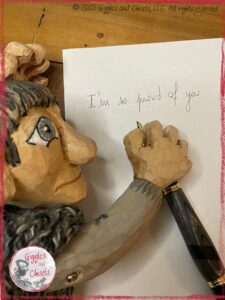 Maurice, a wooden puppet, writing I am so proud of you on a piece of paper