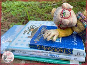 A picture of Mme Rigolotte, a wooden puppet, outside, on a pile of 5 picturebooks
