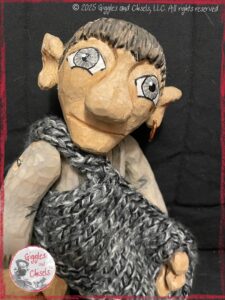 Maurice, a wooden puppet, trying to put his jacket on