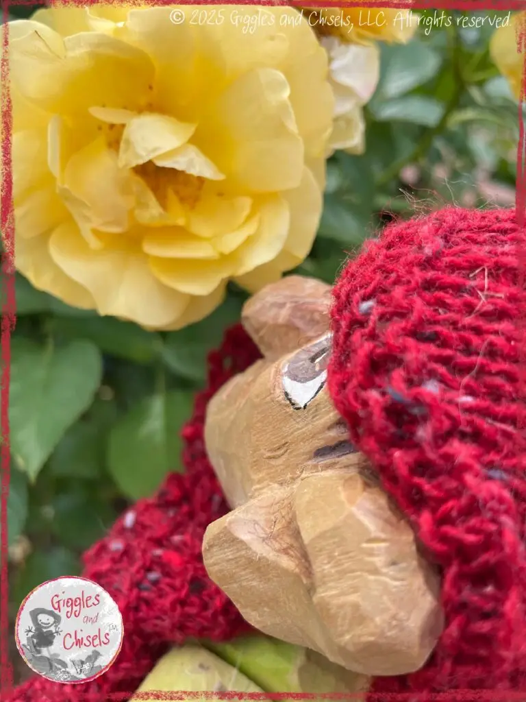 Pierre qui Roule, a wooding puppet, smelling a yellow rose
