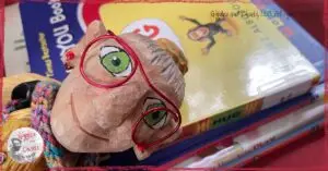 Mme Rigolotte, a wooden puppet, on the top of a pile of picturebooks