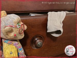 Mme Rigolotte, a wooden puppet, in front of a drawer full of socks