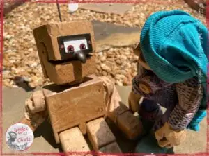 Petite Clothilde, a wooden puppet, looking at a robot puppet