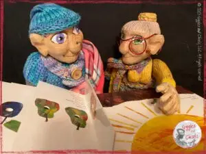 Petite Clothilde and Mme Rigolotte, two wooden puppets, reading a book together