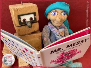 Petite Clothilde, a wooden puppet, reading with a wooden robot