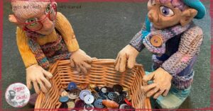 Mme Rigolotte and Petite Clothilde, two wooden puppets, looking at a baskets full of buttons