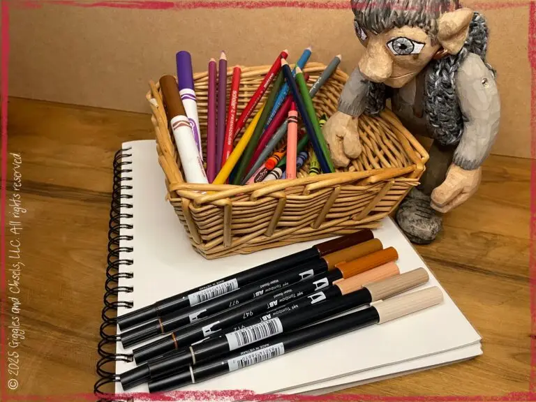 Maurice, a wooden puppet, in front of markers and paper