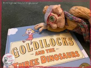 Mme Rigolotte, a wooden puppet, on the top of a picturebook from Mo Willems