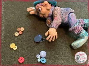 Petite Clothilde, a wooden puppet, sorting buttons by colors