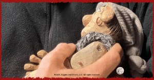 Maurice, a wooden puppet, cuddled in the arm of a human friend