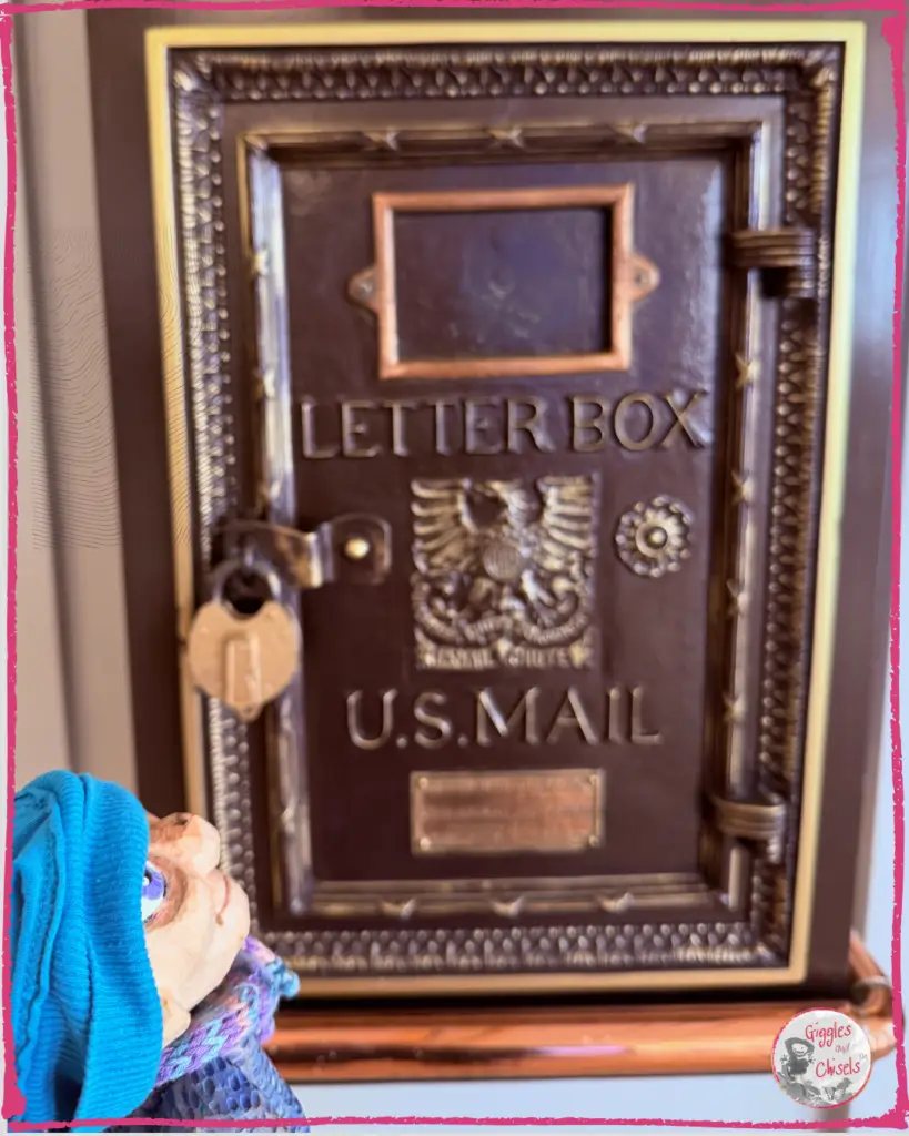 Petite Clothilde, a wooden puppet, looking at a mail box