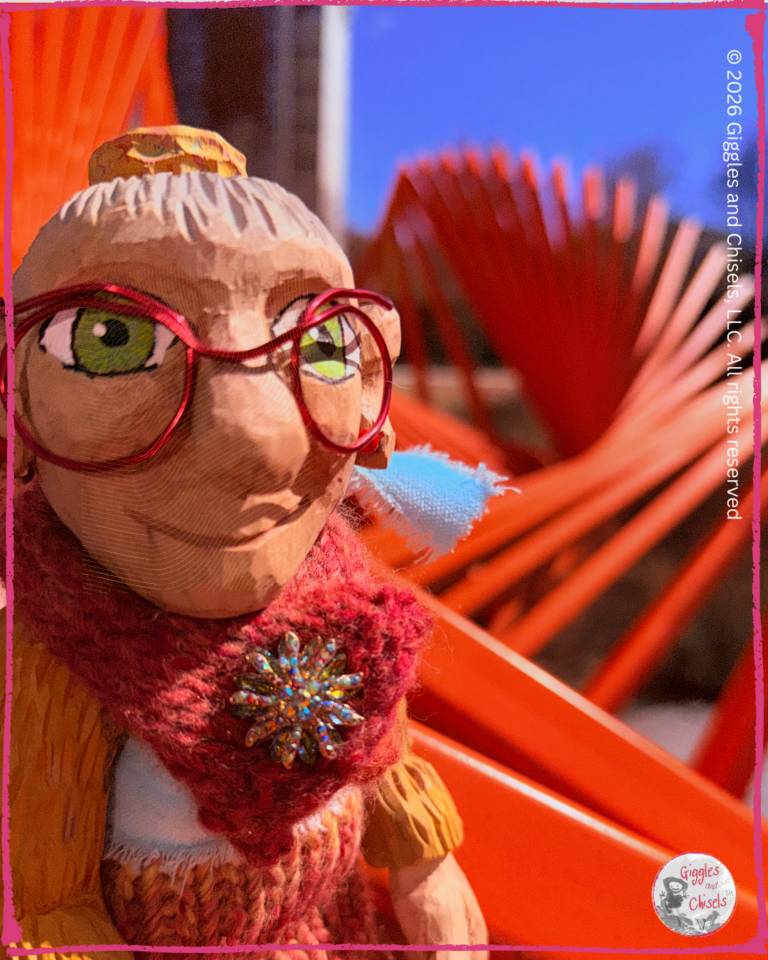 Mme Rigolotte, a wooden puppet, in front of a sculpture