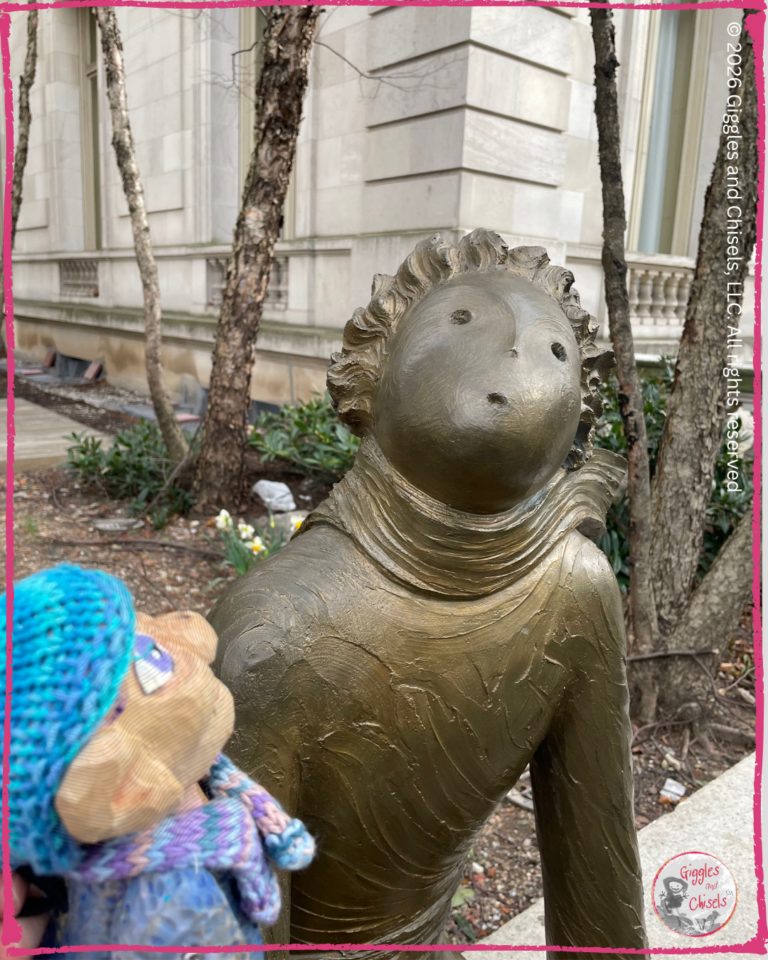 Petite Clothilde, a wooden puppet, in front of a sculpture of the little prince