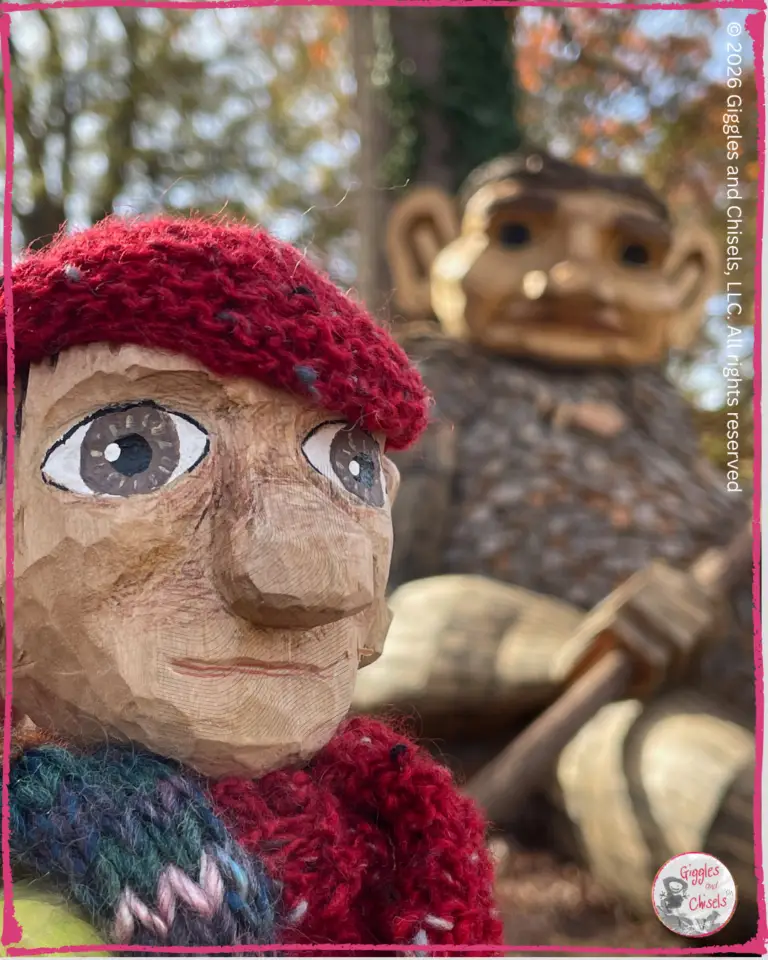Pierre Qui Roule, a wooden puppet, in front of a wooden sculpture of a troll
